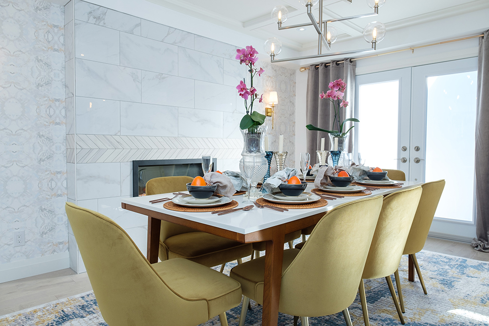 Dining table with golden chairs around it.  Two orchids sit in vases on top of the table.